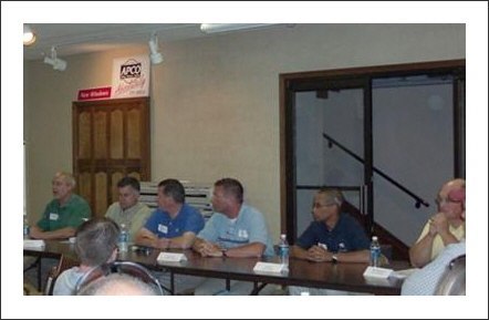 group of apco employees sitting at a table in a meeting