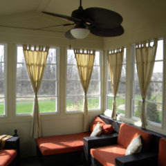 sunroom with red and black furniture windows all around and yellow curtains