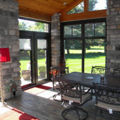 sunroom with hardwood flooring stone walls new doors and wooden ceiling