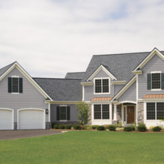 light grey home with double two car garage green lawn and clear blue skies